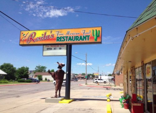 Sign for Rosita's Fine Mexican Food Restaurant with a cowboy statue outside, bright blue sky in the background.