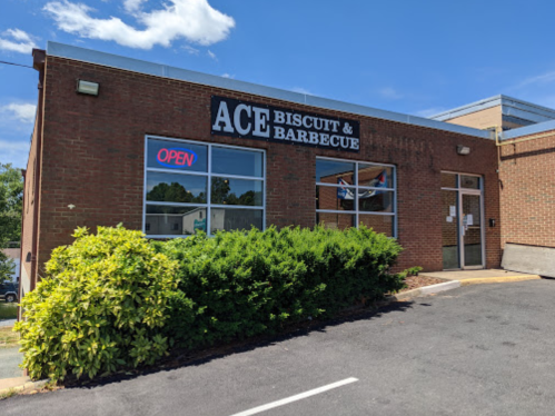 Exterior of Ace Biscuit & Barbecue restaurant with an "Open" sign and greenery in front under a clear blue sky.