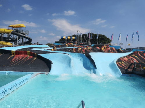 A water park featuring colorful slides and a winding blue waterway under a clear blue sky.
