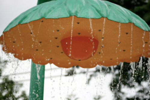 A colorful water umbrella with droplets cascading down, set against a blurred green background.
