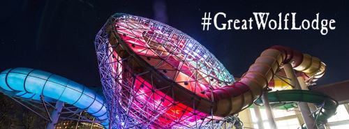 Colorful water slides illuminated at night, featuring the hashtag #GreatWolfLodge.