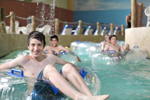 A group of boys enjoying a water park, floating on inner tubes in a lazy river.