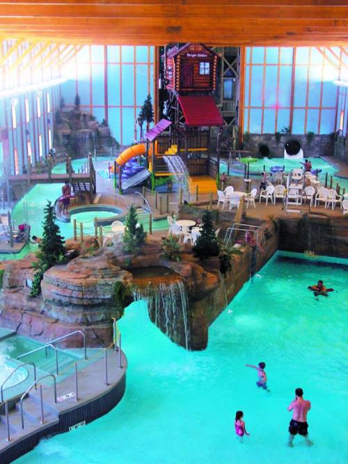 Indoor water park featuring slides, a play structure, and a pool with children swimming and lounging around.