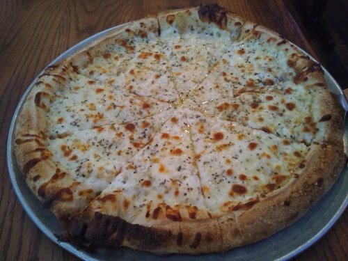 A large, round pizza with a golden crust, topped with melted cheese and sprinkled with herbs, cut into slices.
