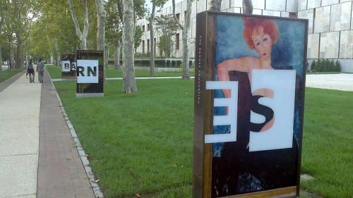 Art installations featuring bold letters and a colorful painting, set in a landscaped outdoor area with trees.