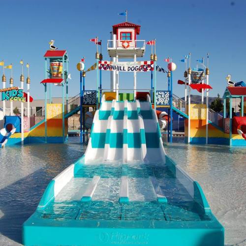 Colorful water slide with a lifeguard tower and playful decorations in a sunny water park setting.