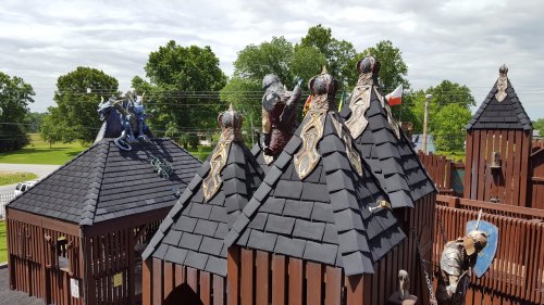 A whimsical playground featuring castle-like structures with dragon sculptures on the rooftops under a cloudy sky.
