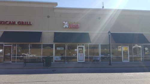 Exterior of a storefront with green awnings, featuring a sign for "Aloha & Boba" and a nearby Mexican grill.