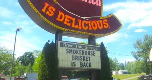A colorful restaurant sign announces "Smokehouse Brisket is back" with a drive-thru service option.