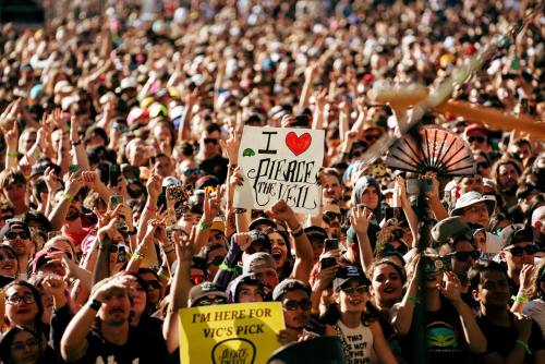 A large crowd at a concert holds up a sign that says "I ❤️ Peace the World," with many people cheering and enjoying the event.