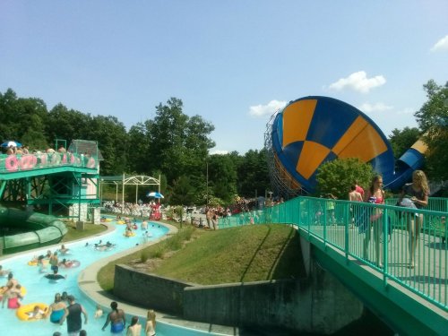 A water park scene with a lazy river, water slides, and a large colorful water ride in the background.