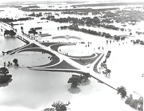 Aerial view of a flooded landscape, with submerged roads and trees, showcasing extensive water coverage.