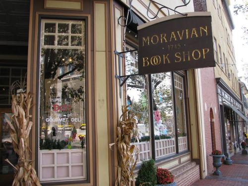 Sign for Moravian Book Shop hangs above a storefront, with decorative corn stalks and a view of the street outside.