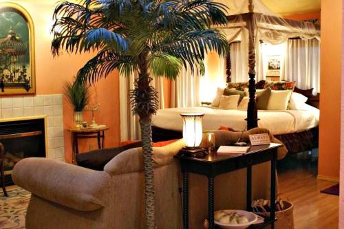 Cozy bedroom with a four-poster bed, palm tree decor, and warm lighting, creating a relaxing atmosphere.