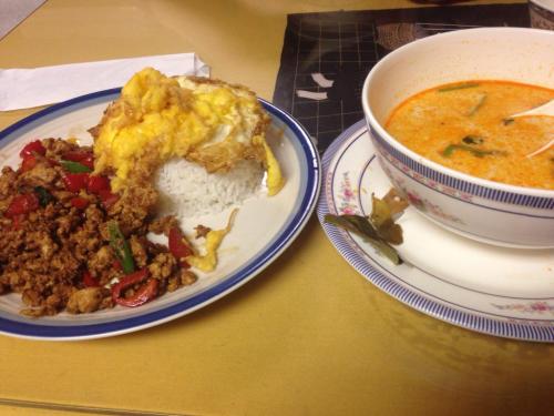 A plate of rice topped with an omelet and stir-fried meat with vegetables, alongside a bowl of creamy soup.