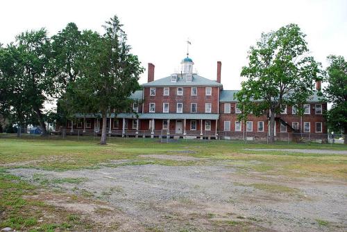 Historic brick building with a central dome, surrounded by trees and a grassy area.