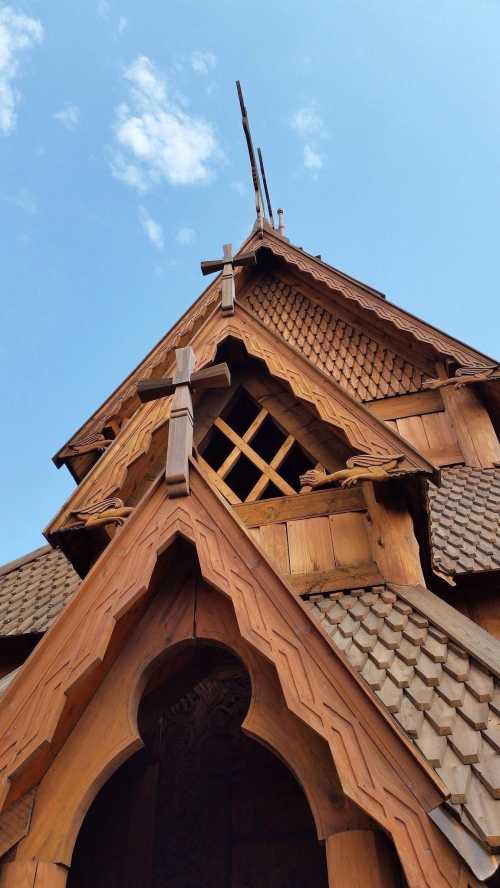 A close-up of a wooden church roof with intricate carvings and a clear blue sky in the background.