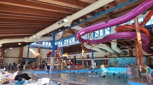 Indoor water park featuring a large pool, colorful water slides, and children playing in a fun, vibrant environment.