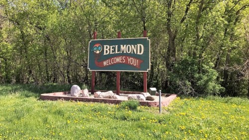 Sign reading "Belmond Welcomes You!" surrounded by greenery and rocks.