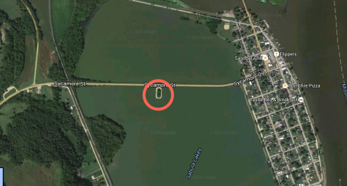 Aerial view of a water body with a road labeled Sycamore St, featuring a circular area highlighted in red.