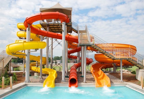 Colorful water slides twist and turn above a pool, set against a cloudy sky.