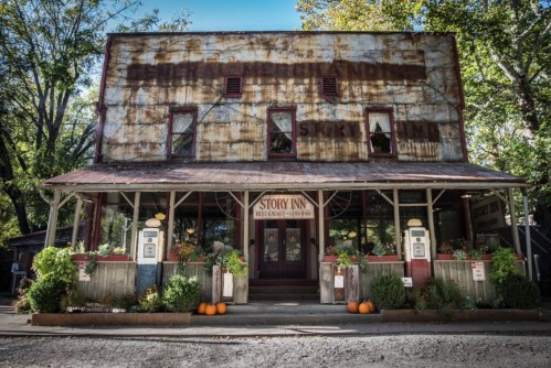 Rustic building with a weathered facade, featuring a sign for "Story Inn" and decorated with pumpkins and flowers.