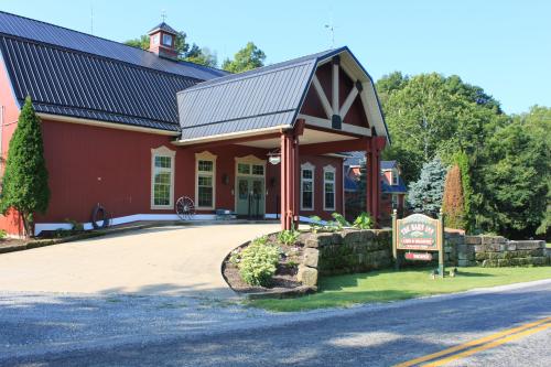 A red building with a black roof, featuring a welcoming entrance and landscaped surroundings, set along a rural road.