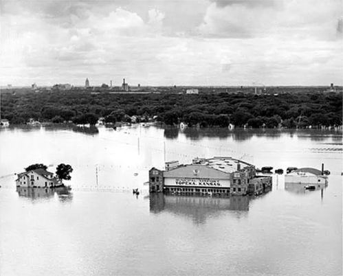 Aerial view of a flooded area with submerged buildings and trees, showcasing the extent of the water.