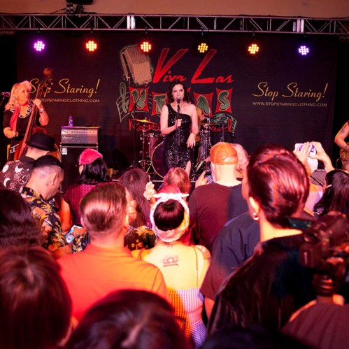 A lively performance at a music event, with a singer on stage and an engaged audience in front.