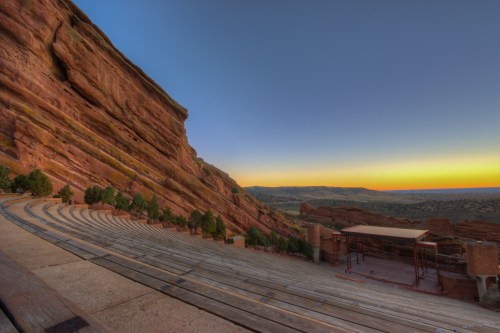A panoramic view of Red Rocks Amphitheatre at sunset, showcasing the natural rock formations and empty seating.
