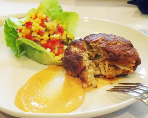 A plate featuring a savory chicken dish with a creamy sauce, accompanied by a fresh mango salad and lettuce.
