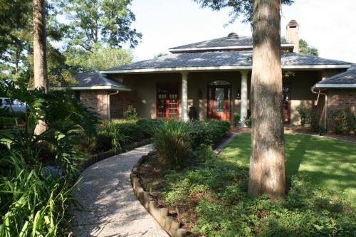 A charming house with a landscaped front yard, featuring a winding path and lush greenery.