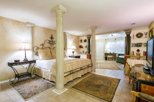 Cozy bedroom with a large bed, decorative columns, and warm lighting, featuring rugs and elegant furnishings.