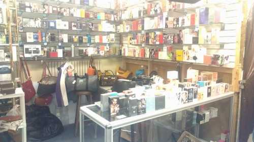 A cluttered retail space filled with various perfume boxes, bags, and display shelves.