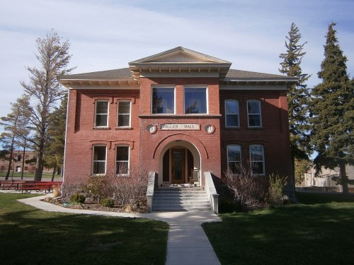Historic brick building with a central entrance, surrounded by trees and a grassy area, labeled "Miller Hall."