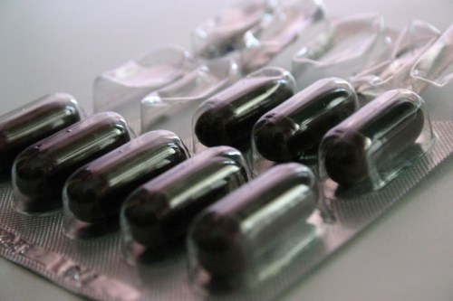 Blister pack containing several dark capsules on a light background.