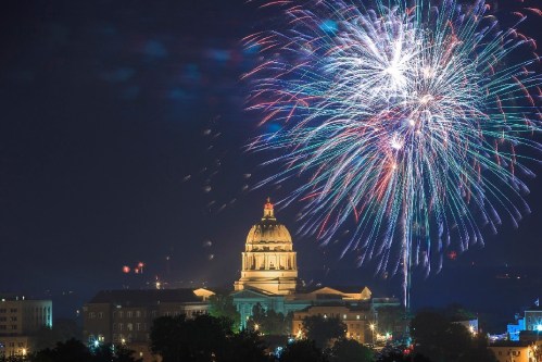 Fireworks illuminate the night sky above a historic building with a dome, creating a festive atmosphere.