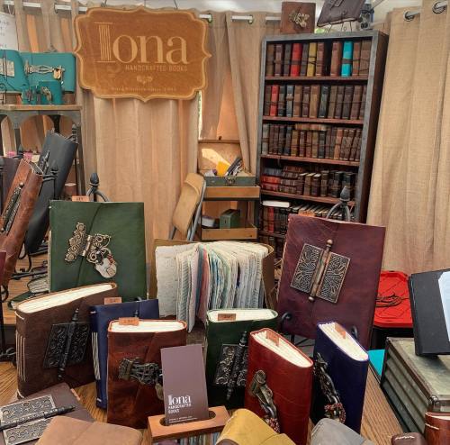 A display of handcrafted books with various colorful covers and decorative elements, set in a cozy booth.