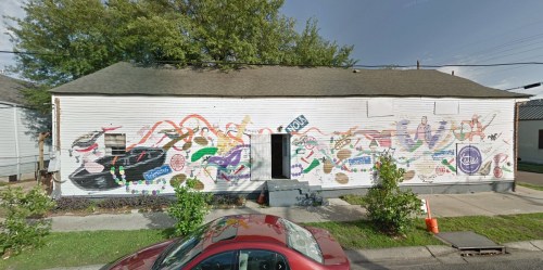 A colorful mural covers the side of a white building, featuring various artistic designs and patterns.