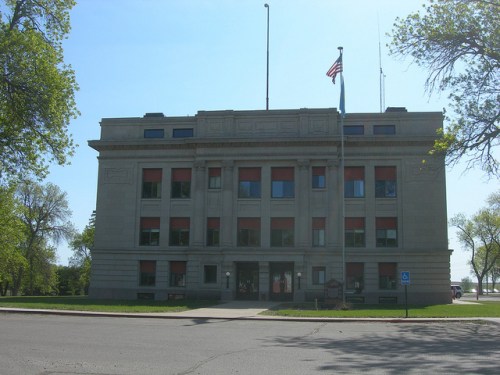 Historic building with a symmetrical facade, large windows, and flags, set against a clear blue sky.