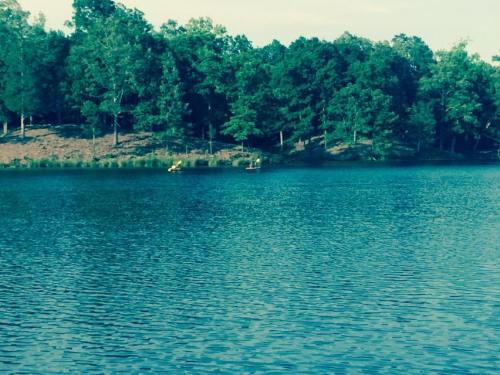 A serene lake surrounded by trees, with two small boats visible on the water.