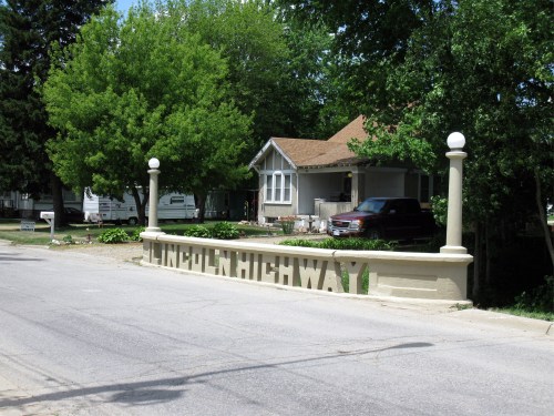Sign marking the Lincoln Highway, with a house and trees in the background.