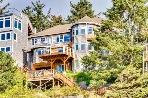 A large, multi-level house with balconies, surrounded by trees on a hillside.