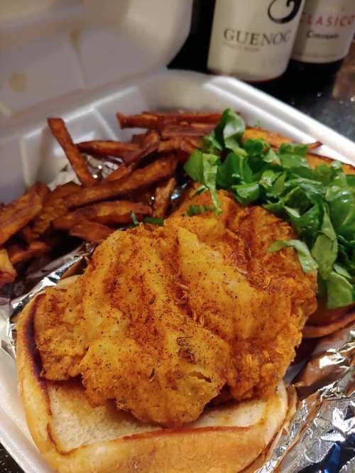 A fried chicken sandwich with lettuce on a bun, served with a side of crispy fries.