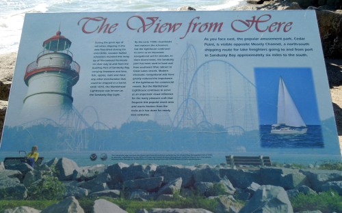 Sign describing the view from Cedar Point, featuring a lighthouse, sailboat, and scenic waterfront.