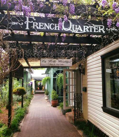 A charming pathway lined with greenery and shops, featuring a sign that reads "French Quarter" above.