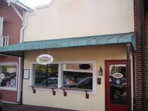 A storefront with a green awning, red door, and a sign reading "Locals" on a sunny day.