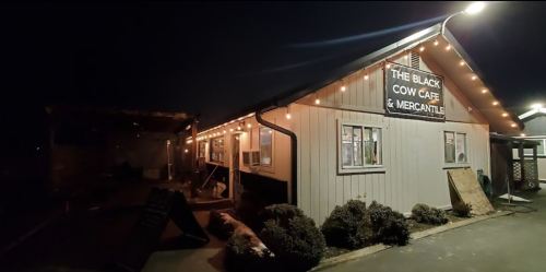 A cozy café and mercantile building illuminated by string lights at night.