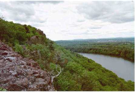 A scenic view of a river winding through lush green hills under a cloudy sky.