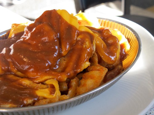 A close-up of a dish featuring fries topped with melted cheese and a rich brown gravy.